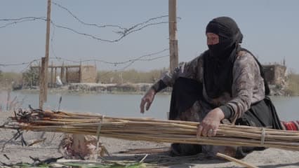 A woman grilling fish on reeds